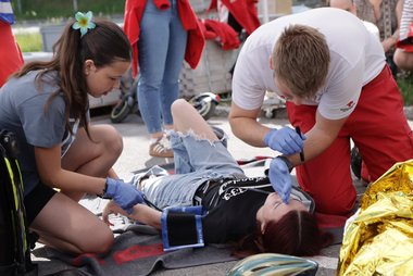 Rettungssanitäter und JRK-Kind versorgen eine Verunfallte in einem Szenario