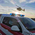 Notarztfahrzeug parkt, dahinter hebt ein Rettungshubschrauber ab