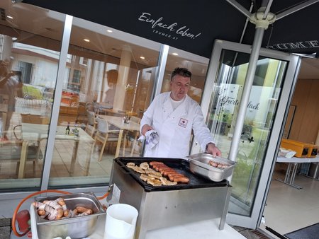 Ein Koch grillt Fleisch und Würstel