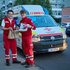 Zwei Rettungssanitäter stehen vor ihrem Auto und halten beide ein toll gefülltes Versorgungssackerl hoch mit Essen für den Tag