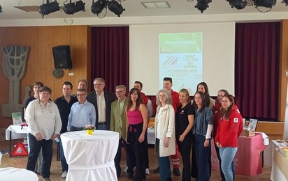 Gruppe von Teilnehmer:innen beim Gesundheitstag in Enzersdorf mit Vertreter:innen des Roten Kreuzes und Aussteller:innen