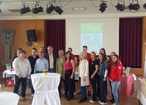 Gruppe von Teilnehmer:innen beim Gesundheitstag in Enzersdorf mit Vertreter:innen des Roten Kreuzes und Aussteller:innen