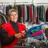 Eine Mitarbeiterin im Rotkreuz-Markt für Bekleidung steht zwischen den Kleiderständern auf denen die Ware präsentiert wird.