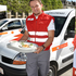 Ein junger Mann in Rotkreuz-Uniform hält ein Tablett mit Speisen in der Hand.