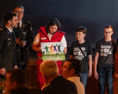 Überreichung der Jugendfitzertifikate für Innsbruck Land / Kinder mit Betreuer und Schild auf der Bühne