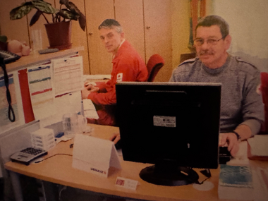 Büroszene in der Verwaltung, zwei Mitarbeiter sitzen vor einem PC.