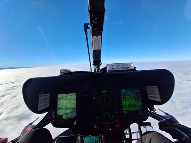Blick aus dem Cockpit des Notarzthubschraubers Christophorus 6 bei Tag und über den Wolken aus Sicht des Piloten.