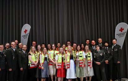 Gruppenfoto mit Rotkreuz-Mitarbeiterinnen. Ein Teil in grauen Uniformen, ein Teil mit gelben Westen.