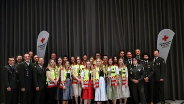 Gruppenfoto mit Rotkreuz-Mitarbeiterinnen. Ein Teil in grauen Uniformen, ein Teil mit gelben Westen.