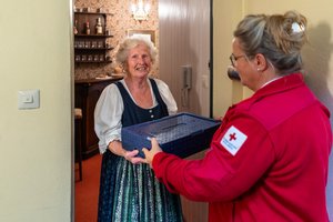 Eine Zuhause Essen Mitarbeiterin liefert an eine Seniorin