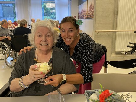 Eine Bewohnerin und Mitarbeiterin des Seniorenwohnhauses Hallein mit einem Eisbecher in der Hand