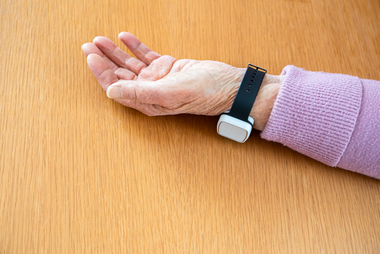 Arm mit Rufhilfe-Uhr liegt am Boden