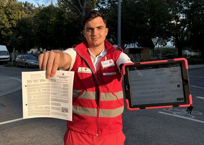 Ein D2D-Werber steht in Rotkreuz-Uniform und hält ein Mitgliederformular, sowie ein Tablet-PC in der Hand.