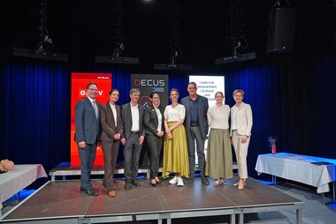 Vorstand des DECU-Netzwerks mit Gästen auf einer Bühne in Wien.