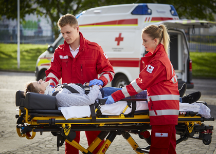 Ein Zivildiener und eine Mitarbeiterin im freiwilligen Sozialjahr betreuen eine Patientin auf der Trage.