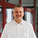 Porträt von Herbert Girstmair, Bereichsleiter Rettungs- und Krankentransport, Ambulanzdienste. Er steht im weißen Hemd vom Roten Kreuz