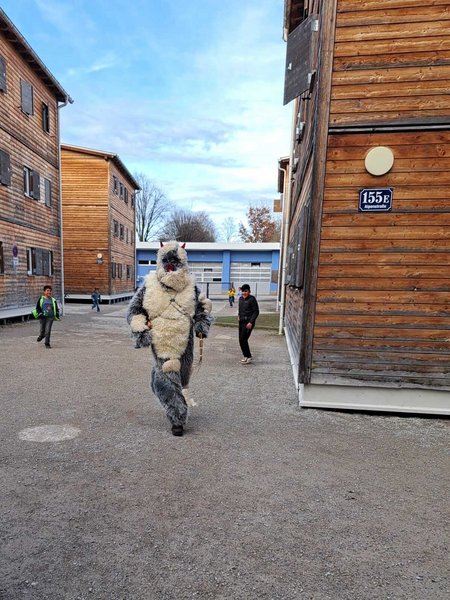 Der Krampus am Gelände des Flussbauhofes, im Hintergrund einige Kinder, die dort leben.