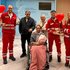 Rotkreuz-Mitarbeiter:innen mit der Patient:innen im Rollstuhl, sie hält einen Blumenstrauß in der Hand.