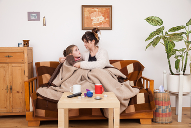 © ÖRK/Nadja Meister Eine Mutter sitzt mit ihrem kleinen Mädchen auf der Couch. Sie sind zugedeckt, weil die Wohnung kalt ist.