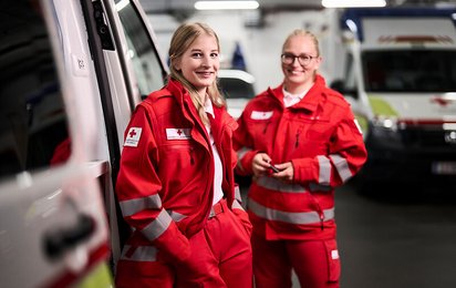 Zwei junge Frauen in RK Uniform vor dem Rettungsauto