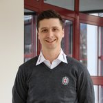 Porträt vom Geschäftsführer des Rotes Kreuzes in Osttirol - Alexander Perry. Er steht im grauen Pullover vom Roten Kreuz