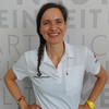 Dr. Andrea Schmid Schirmer - © Rotes Kreuz Tirol Christine Widmann Portrait von Andrea Schmid Schirmer im Roten Kreuz Poloshirt vor der Wand mit den Rotkreuz Grundsätzen