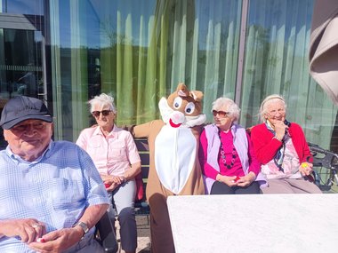 Der Osterhase sitzt mit Bewohnerinnen auf einer Bank
