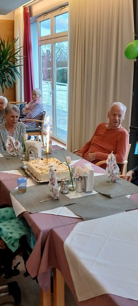 Eine Frau am Geburtstagsfest, rund um sie sieht man Ballone und Kuchen. 