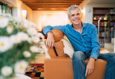 Kinderbuchautor Thomas Brezina sitzt auf einer Couch.