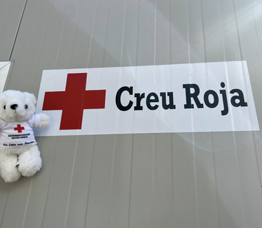 Bärli befindet sich vor einer Dienststelle des Roten Kreuzes in Barcelona. Hinter ihm sieht man die Aufschrift "Creu Roja", also "Rotes Kreuz" auf spanisch.