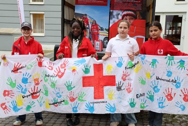 Kinder mit einem Rotkreuzbanner in der Hand