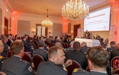 Festsaal mit Gästen und Redner:innen auf einer Bühne