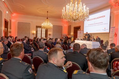 Festsaal mit Gästen und Redner:innen auf einer Bühne