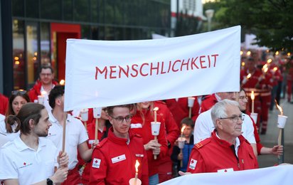 Rotkreuzler:innen tragen ein Banner mit dem Grundsatz "Menschlichkeit"