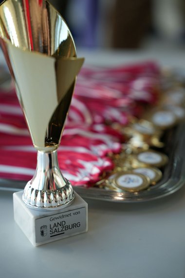 Der Pokal für das Sieger-Team des Pinguin Cups, im Hintergrund ein Tablett mit Medaillen.