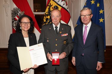 Landeshauptmann Wilfried Haslauer und Landesrätin Daniela Gutschi bei der Überreichung der Feuerwehr- und Rettungsmedaille für 50 Jahre an Hauptsanitätsmeister Erich Kupelwieser aus Bischofshofen.