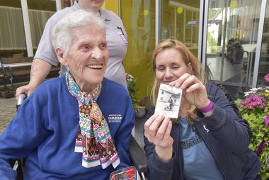 Rosa mit einer Dame, die das alte Foto von Rosa mit ihrer Vespa hält