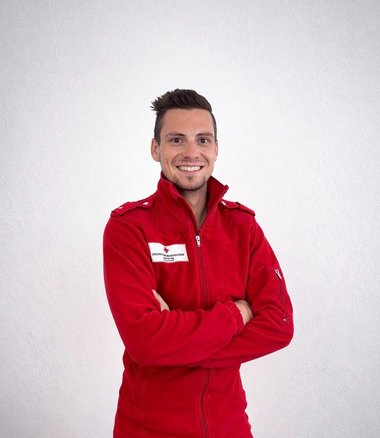 Ein Sanitäter mit roter Jacke.