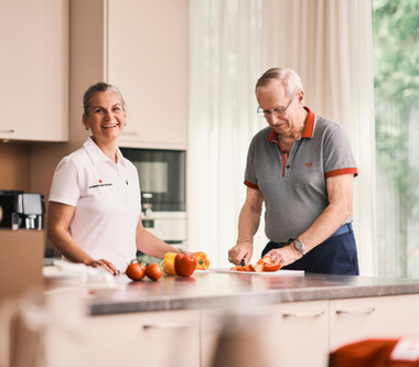 © OÖRK / Robert Maybach Eine Heimhelferin bereitet eine Obstjause mit ihrem Kunden vor. Sie stehen in der Kühe und beide helfen mit.