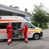 Ein Rettungsauto und davor stehen ein Vater mit seinem Sohn. Alfons und Andreas.