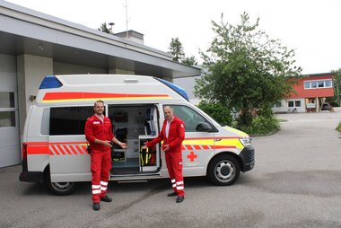 Ein Rettungsauto und davor stehen ein Vater mit seinem Sohn. Alfons und Andreas.