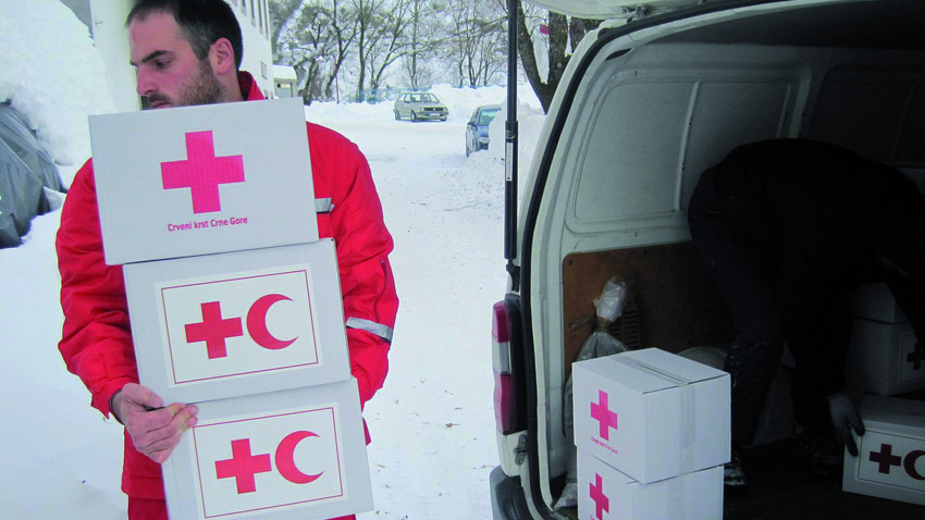 Montenegro. Februar 2012. Ein Rotkreuzhelfer lädt Hilfsgüter aus einem Transporter. Im Hintergrund tiefer Schnee