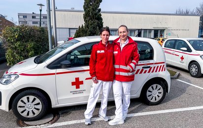 Sonja und Barbara stehen in Uniform vor einem ihrer Dienstautos