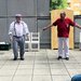 Der Clown steht links neben einem Pflege-Mitarbeiter, der die Arme seitlich wegstreckt
