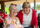 Eine Reiseteilnehmerin mit einer Rotkreuz-Mitarbeiterin, beide lachen gklücklich in die Kamera