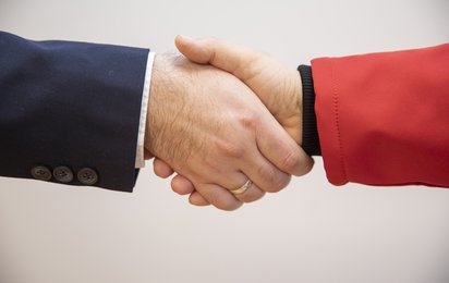 Handschlag mit Person in Businessoutfit und Person in Rotkreuz-Uniform