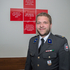 Mag. Daniel Miedl - Bezirksfreiwilligenkoordinator - steht in Ausgangsuniform vor einem Roten Kreuz, in dem einige Sätze des Leitbildes gedruckt sind.