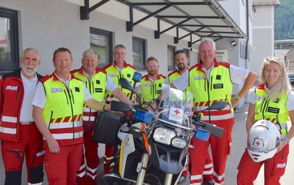Mitarbeiter:innen vom Roten Kreuz Lungau stehen gemeinsam vor dem neuen Einsatz-Motorrad