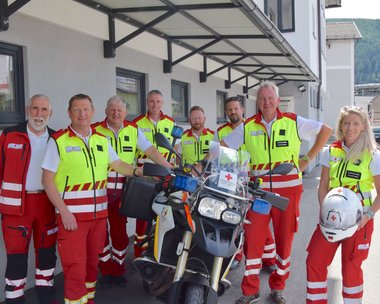 Mitarbeiter:innen vom Roten Kreuz Lungau stehen gemeinsam vor dem neuen Einsatz-Motorrad