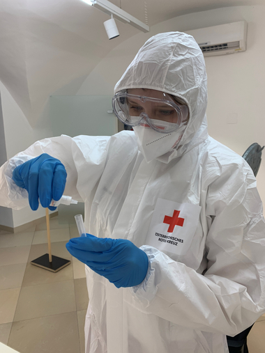 Massentests in Niederösterreich, eine Testerin in vollem Testanzug die gerade einen Abstrich macht.